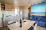 Soggiorno moderno con cucina nel lodge Park Riviera 2 camere al Campeggio Park Umag, Croazia, con divano blu.