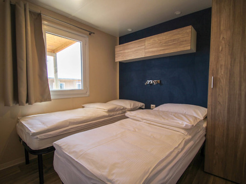 Bedroom at Park Riviera '2 bedrooms' in Campsite Park Umag, Croatia, featuring twin beds and minimalist decor.