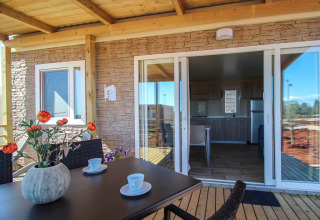 Covered terrace with table and chairs in front of Park Riviera lodge at Campsite Park Umag, Croatia.
