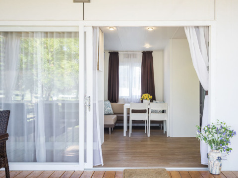 Ingresso di un lodge moderno con porte scorrevoli aperte, tavolo da pranzo e fiori, Park Riviera EVO.