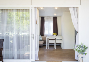 Entrance to a modern lodge with open sliding doors, dining area, and flowers at Park Riviera EVO, Croatia.