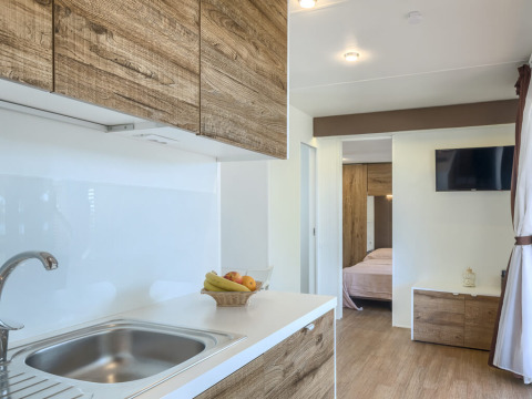 Modern Park Riviera «EVO» lodge kitchen with wooden details, fruit basket, and bedroom view, Park Umag.