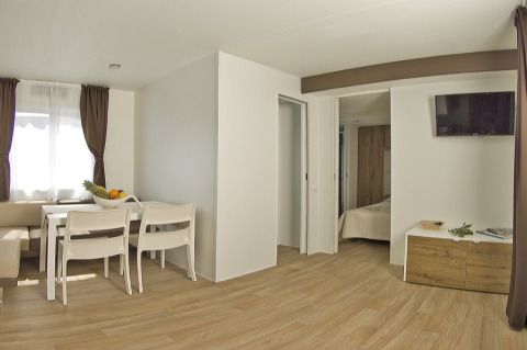 Intérieur moderne et lumineux d’un lodge avec salle à manger, chambre et TV au Park Riviera EVO, Park Umag.