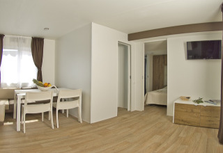 Intérieur moderne et lumineux d’un lodge avec salle à manger, chambre et TV au Park Riviera EVO, Park Umag.