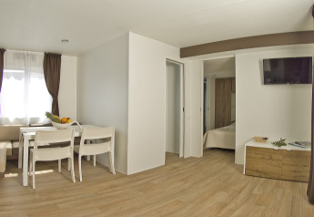 Interno moderno e luminoso di una casa vacanze con zona pranzo, camera e TV al Park Riviera EVO, Park Umag.