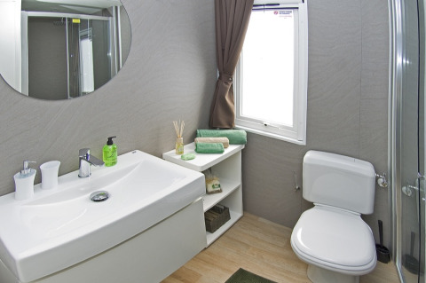 Salle de bain moderne avec lavabo, miroir, WC et étagère au Park Riviera «EVO», Camping Park Umag, Croatie.