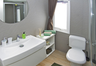 Salle de bain moderne avec lavabo, miroir, WC et étagère au Park Riviera «EVO», Camping Park Umag, Croatie.