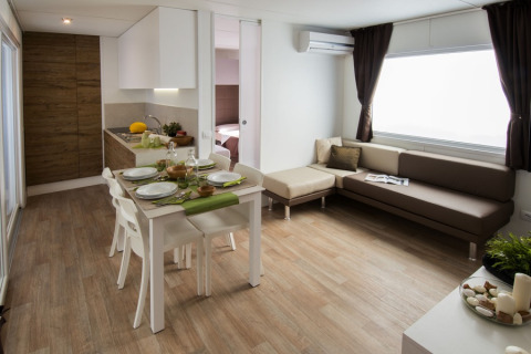 Interno moderno della lodge Park Riviera «EVO» con cucina, zona pranzo e divano al Campsite Park Umag, Croazia.