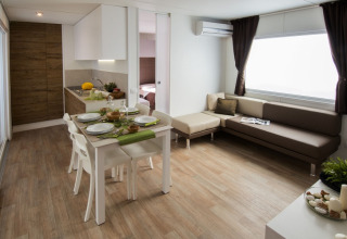 Modern interior of Park Riviera «EVO» lodge with kitchen, dining area and sofa at Campsite Park Umag, Croatia.