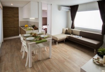 Interno moderno della lodge Park Riviera «EVO» con cucina, zona pranzo e divano al Campsite Park Umag, Croazia.