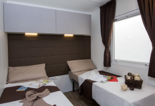 Modern twin room with brown decor, two beds and window at Park Riviera EVO lodge at Campsite Park Umag, Croatia.