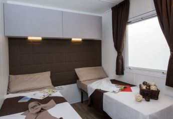 Modern twin room with brown decor, two beds and window at Park Riviera EVO lodge at Campsite Park Umag, Croatia.