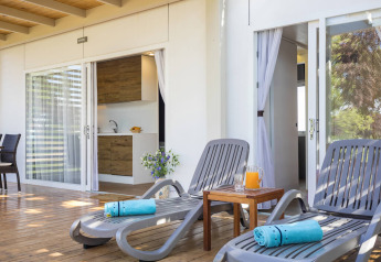 Terrazza soleggiata con lettini, asciugamani blu e succo al Park Riviera «EVO», Campeggio Park Umag, Croazia.