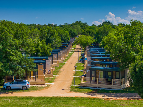 Modern cabins lined up with green trees at Park Riviera «Adria Garden», Campsite Park Umag, Croatia, sunny day.