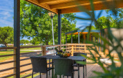 Veranda in legno coperta con tavolo, sedie e cesta di frutta al Park Riviera «Adria Garden» al Campeggio Park Umag, Croazia.