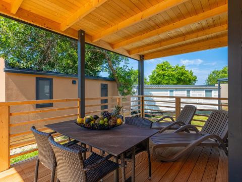 Covered terrace at Park Riviera «Adria Garden», Campsite Park Umag, Croatia, with table, chairs, and loungers.