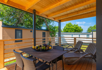 Terrasse couverte au Park Riviera «Adria Garden» du Camping Park Umag en Croatie, avec table et transats.