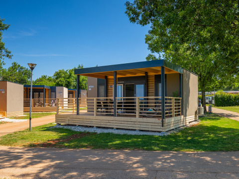 Modern lodge at Park Riviera «Adria Garden» in Campsite Park Umag, Croatia, surrounded by sunny greenery.