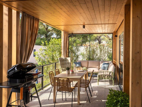 Covered terrace with dining table, lounge sofas, and grill at Hilltop Green Home, Valamar Camping Padova, Croatia.