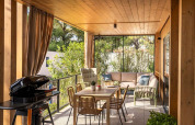 Terrazza coperta con tavolo da pranzo, divani e barbecue al Hilltop Green Home, Valamar Camping Padova, Croazia.