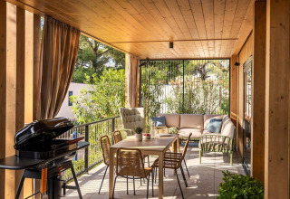 Covered terrace with dining table, lounge sofas, and grill at Hilltop Green Home, Valamar Camping Padova, Croatia.