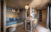 Interno di lodge moderno con cucina compatta, zona pranzo, divano accogliente e dettagli naturali.