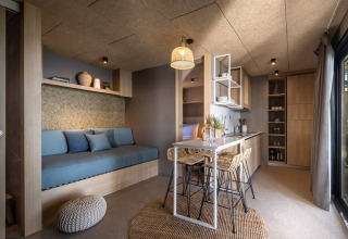 Moderne lodge med kompakt indretning, spisebord, åbent køkken og hyggelig sofa med naturlige farver.
