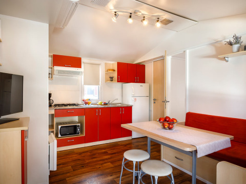 Cocina y comedor modernos dentro de la cabaña Padova Home en Valamar Camping Padova, Croacia, con gabinetes rojos.