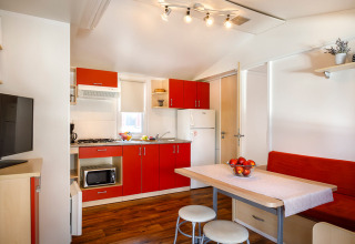 Cocina y comedor modernos dentro de la cabaña Padova Home en Valamar Camping Padova, Croacia, con gabinetes rojos.
