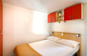 Camera da letto nella cabina Padova Home al Valamar Camping Padova, Croazia, con letto matrimoniale e armadi rossi.