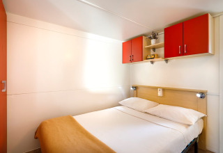 Dormitorio en la cabaña Padova Home en Valamar Camping Padova, Croacia, con cama doble y armarios rojos.