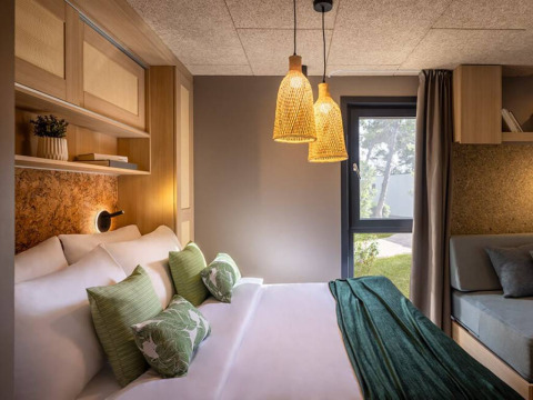 Modern bedroom at Hilltop Green Chalet, Valamar Camping Padova, Croatia, featuring cozy lighting and decor.