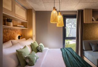 Modern bedroom at Hilltop Green Chalet, Valamar Camping Padova, Croatia, featuring cozy lighting and decor.