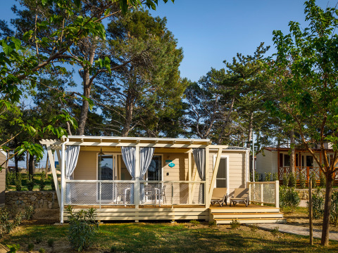 Lodge Marine Home au Valamar Camping Padova en Croatie, terrasse en bois, transats et arbres tout autour.