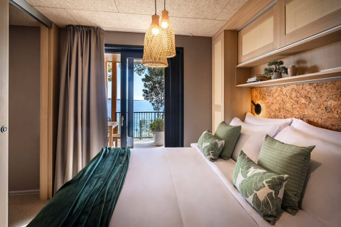 Luxe lodgekamer met groene accenten, zachte verlichting en zeezicht in Valamar Camping Padova, Kroatië.