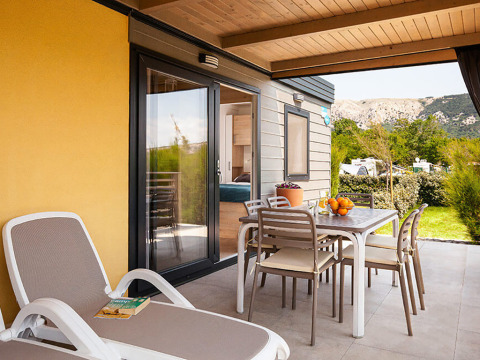 Terras van Sunny Beach Home op Valamar Camping Baška, Kroatië met ligzetel en eettafel buiten.