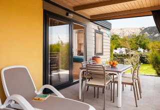 Terras van Sunny Beach Home op Valamar Camping Baška, Kroatië met ligzetel en eettafel buiten.