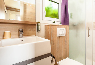 Moderne badkamer met houten details, lavabo, toilet, douche en raam in Sunny Beach Home lodge.