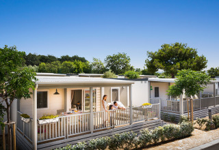 Moderne lodge bij Krk Home in Valamar Camping Krk, Kroatië, met veranda en gasten die buiten ontspannen.