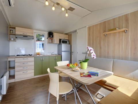 Moderne keuken en eetruimte in Krk Home lodge met groene kasten, eettafel en een orchideeplant.