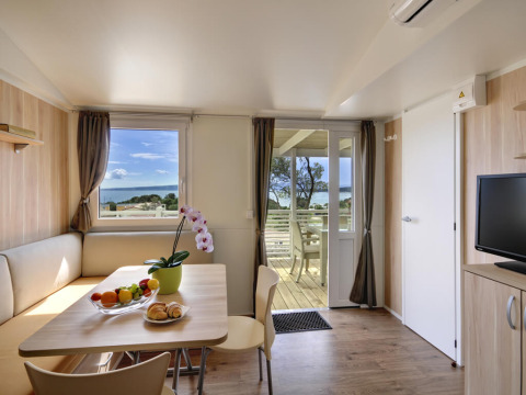 Interieur van Krk Home lodge bij Valamar Camping Krk in Kroatië, met zeezicht en een terras.