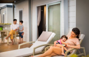 Gezin ontspant op het terras van hun lodge bij Krk Home, Valamar Camping Krk in Kroatië, vrolijke sfeer.