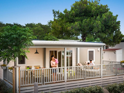 Gezin ontspant op het terras van een moderne lodge in Krk Home, Valamar Camping Krk, Kroatië, omringd door natuur.