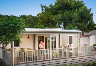 Gezin ontspant op het terras van een moderne lodge in Krk Home, Valamar Camping Krk, Kroatië, omringd door natuur.
