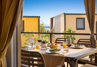 Gedekte eettafel op het terras bij Bella Vista Home in Valamar Camping Krk, Kroatië, met uitzicht.