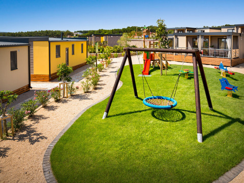 Speelplaats bij Bella Vista Home op Valamar Camping Krk, Kroatië, met moderne lodges en groen gras rondom.