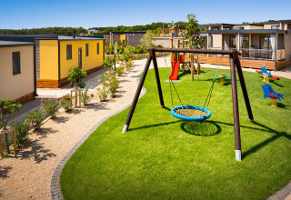 Speelplaats bij Bella Vista Home op Valamar Camping Krk, Kroatië, met moderne lodges en groen gras rondom.