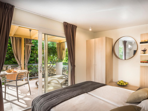 Modernt soveværelse i Bella Vista Chalet på Valamar Camping Krk i Kroatien med terrasse, grønt og spiseplads.
