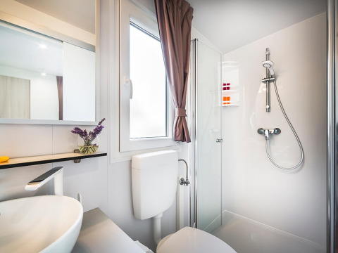 Moderne og rent badeværelse i Bella Vista Chalet med bruser, vindue, spejl og elegant indretning.
