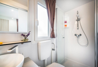 Moderne og rent badeværelse i Bella Vista Chalet med bruser, vindue, spejl og elegant indretning.